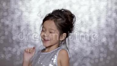 美丽的微笑的小女孩，穿着<strong>银色</strong>的裙子，在<strong>银色</strong>的背景下跳舞。